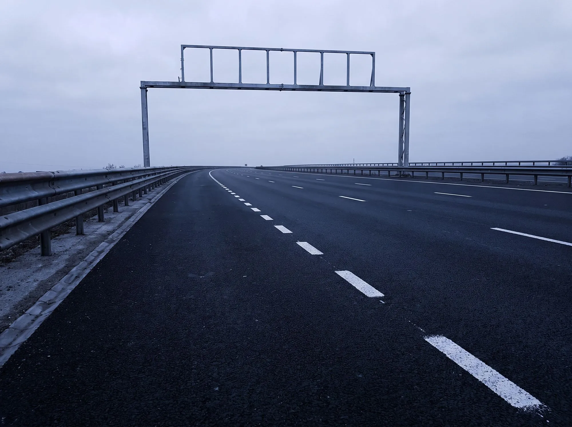 Dreispurige Autobahn in einer Kurve unter grauem Himmel