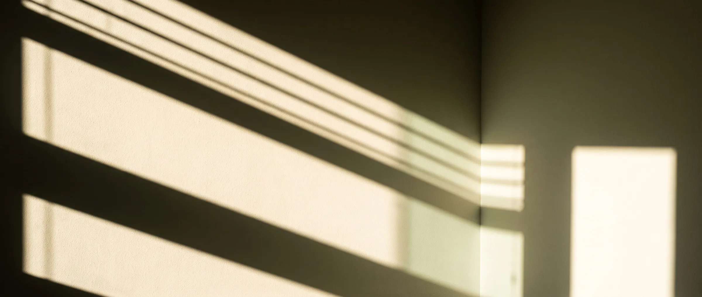 Harte Lichtbänder einer Jalousie auf einer glatten Putzwand