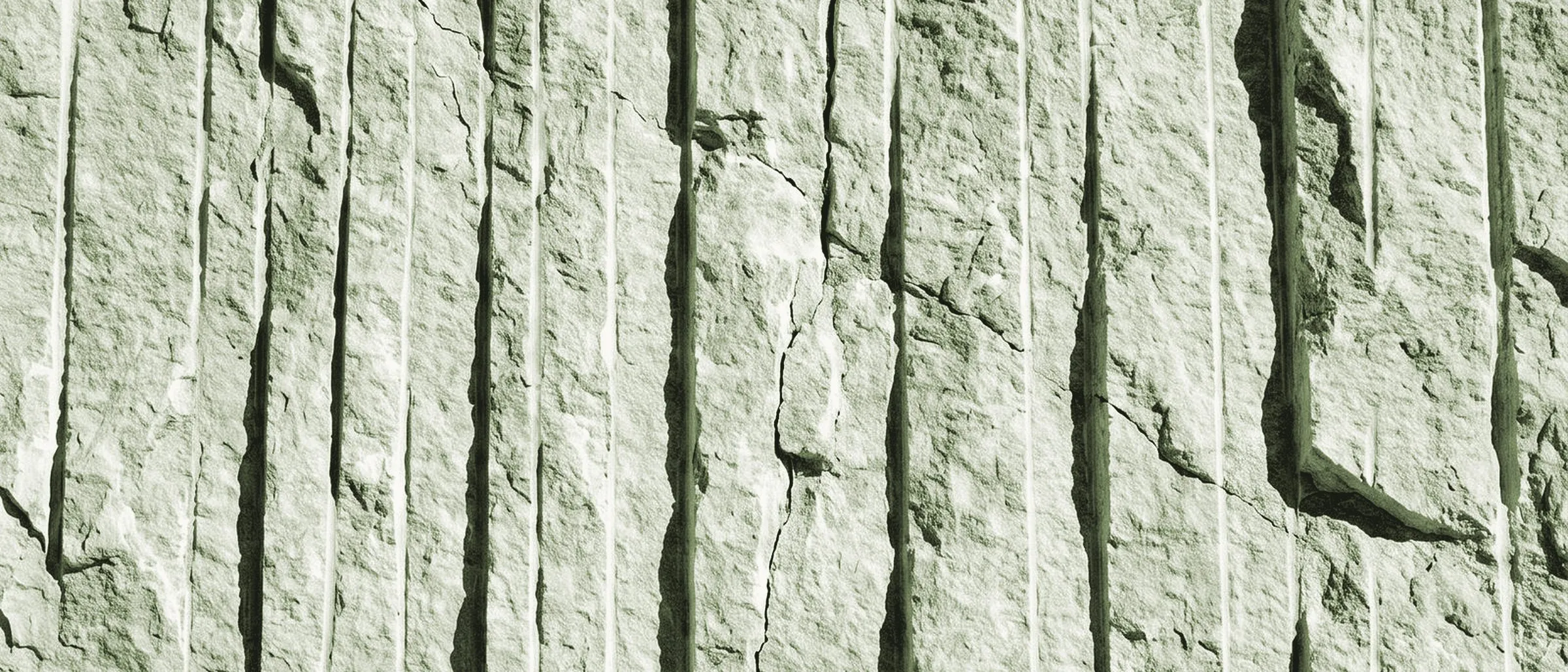 Gebrochene Kalksteinwand mit senkrechten Spuren des Schnitts